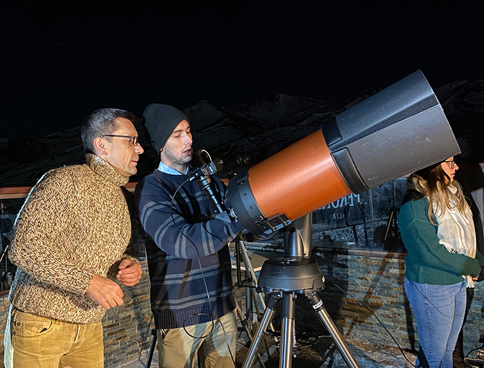 Profesor Thomas Puzia guiando a un estudiante en la observación de un telescopio.