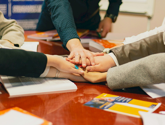 Manos apiladas simbolizando colaboración.