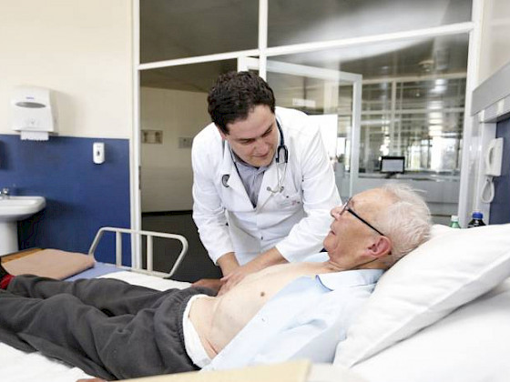Un médico de la Pontificia Universidad Católica de Chile ausculta a un paciente de la tercera edad.