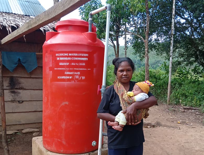 Mujer y su bebé, junto a un estanque de agua domiciliario en Wansar.