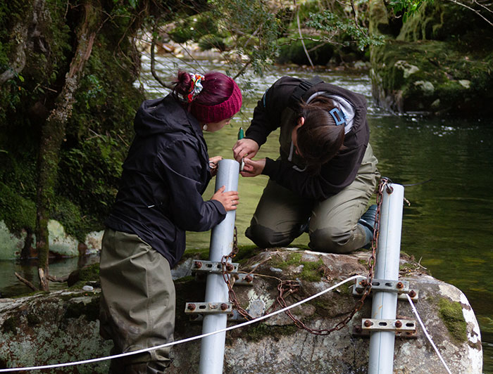 Dos jóvenes instalando equipamiento en un río.
