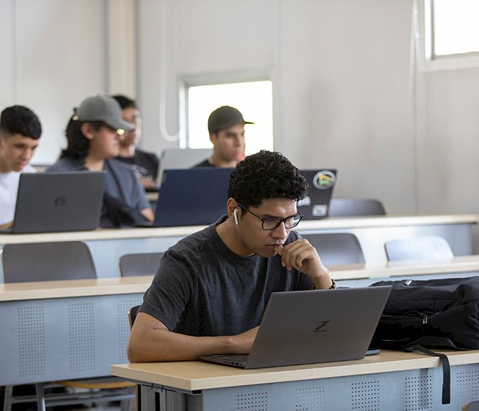 Estudiantes en una sala de clases con sus computadores