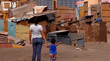 Mujer joven junto a un niño de espaldas observando un campamento.