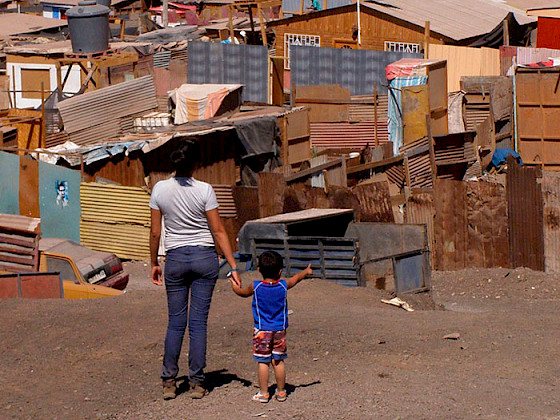 Mujer joven junto a un niño de espaldas observando un campamento.