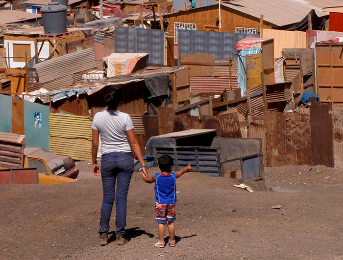 Mujer joven junto a un niño de espaldas observando un campamento.