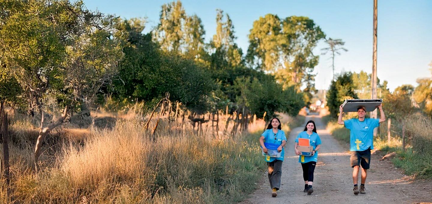 Voluntarios de Capilla País transportando materiales por un camino de tierra.