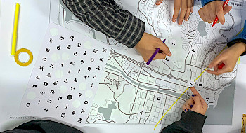 Personas trabajando sobre un mapa y una hoja con iconos.
