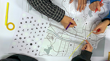 Personas trabajando sobre un mapa y una hoja con iconos.