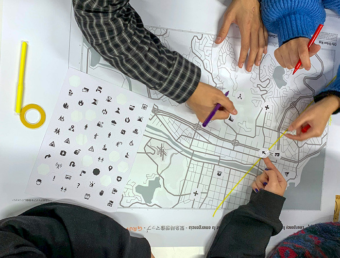 Personas trabajando sobre un mapa y una hoja con iconos.