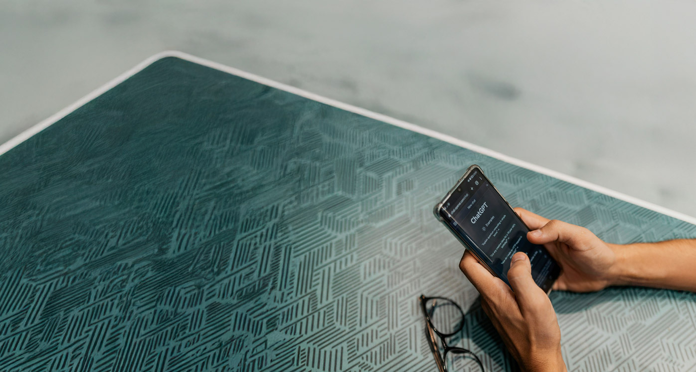 Persona sosteniendo un teléfono con una app de inteligencia articial, junto a unos anteojos