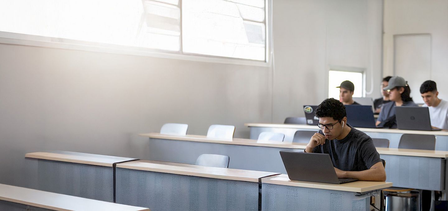 Estudiantes trabajando en computadores en una sala de clases.