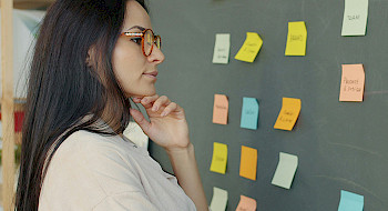 Mujer observando post it en una pizarra