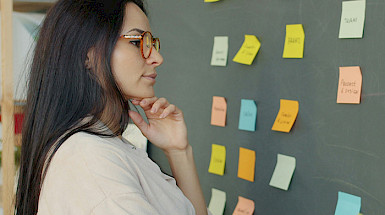 Mujer observando post it en una pizarra