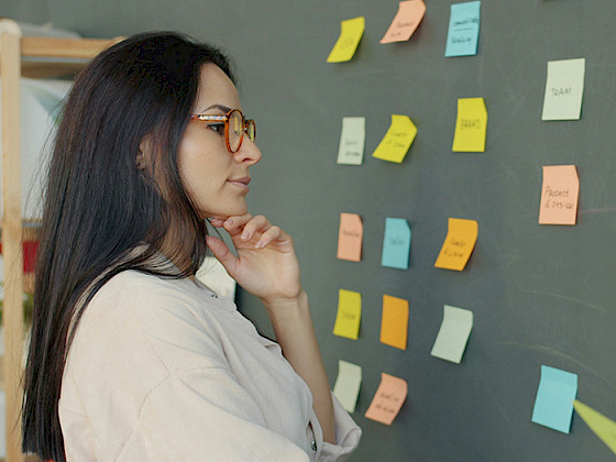Mujer observando post it en una pizarra