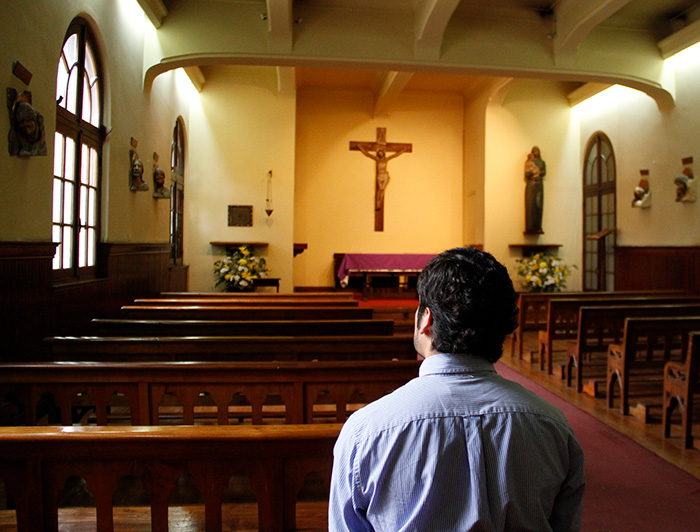 Joven sentado en una capilla.