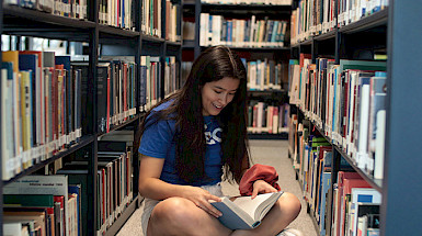 Joven leyendo un libro en una biblioteca