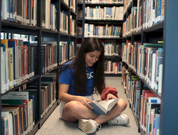 Joven leyendo un libro en una biblioteca