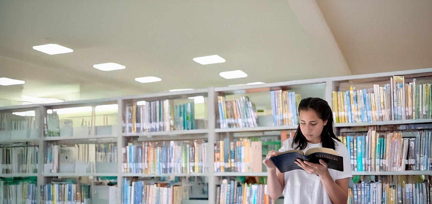 Joven leyendo un libro en la biblioteca