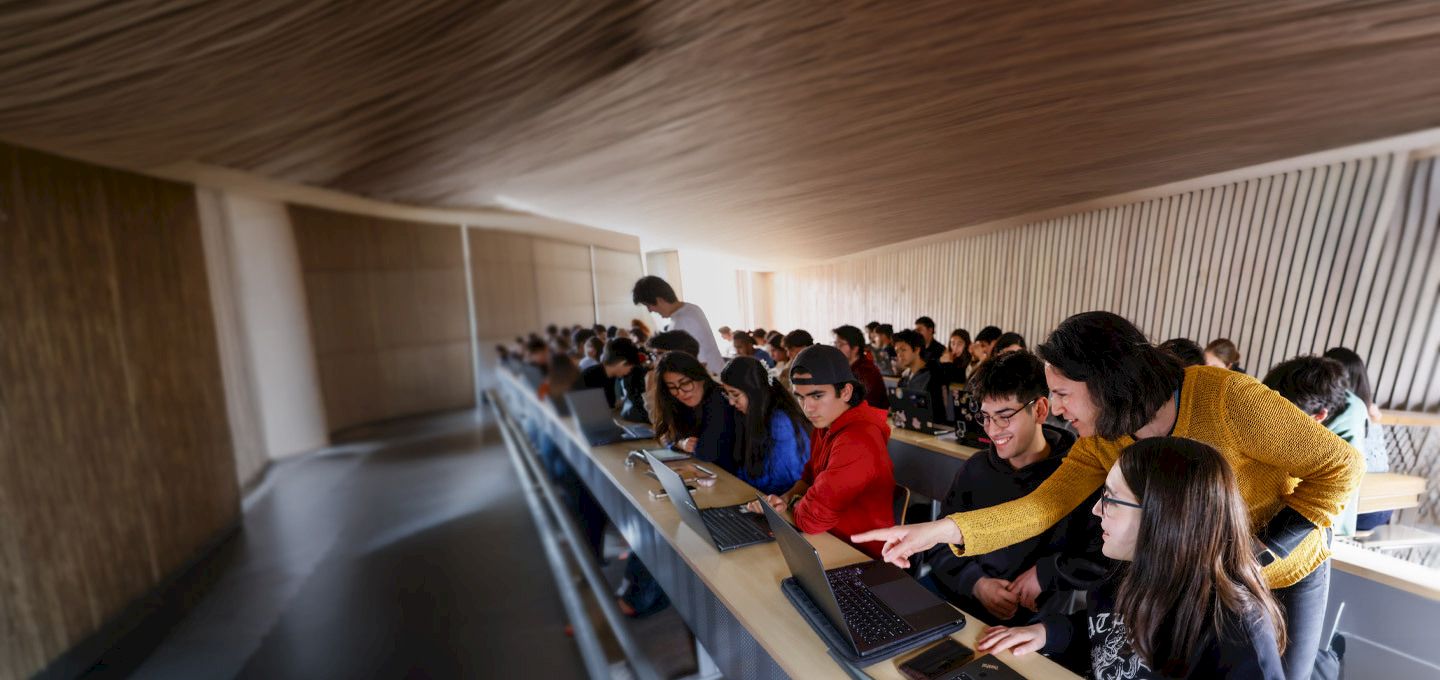 Profesora y estudiantes en sala de clases utilizando notebooks