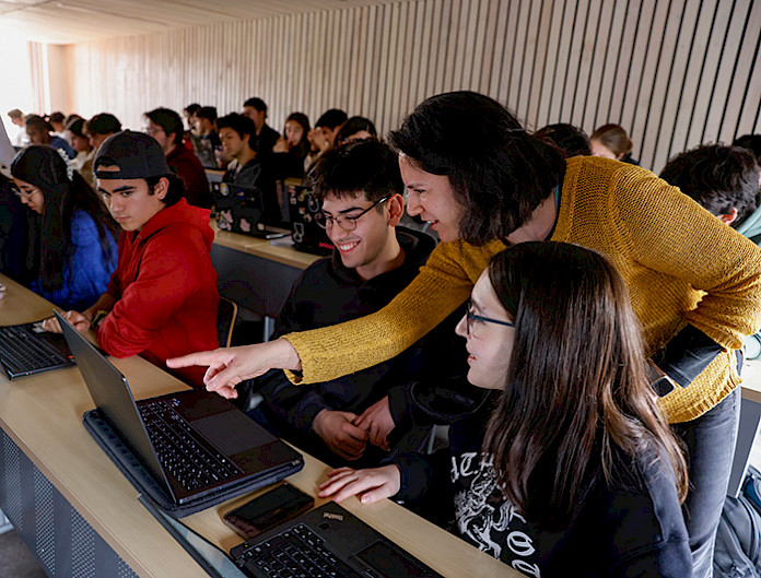 Estudiantes y profesora en clases con un computador