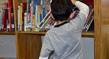 Niño sacando un libro de un estante