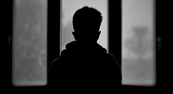 Silueta de un niño de espaldas a una ventana