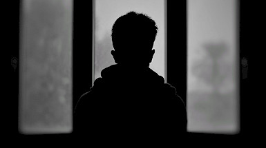 Silueta de un niño de espaldas a una ventana