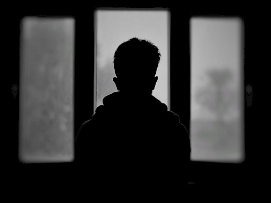 Silueta de un niño de espaldas a una ventana
