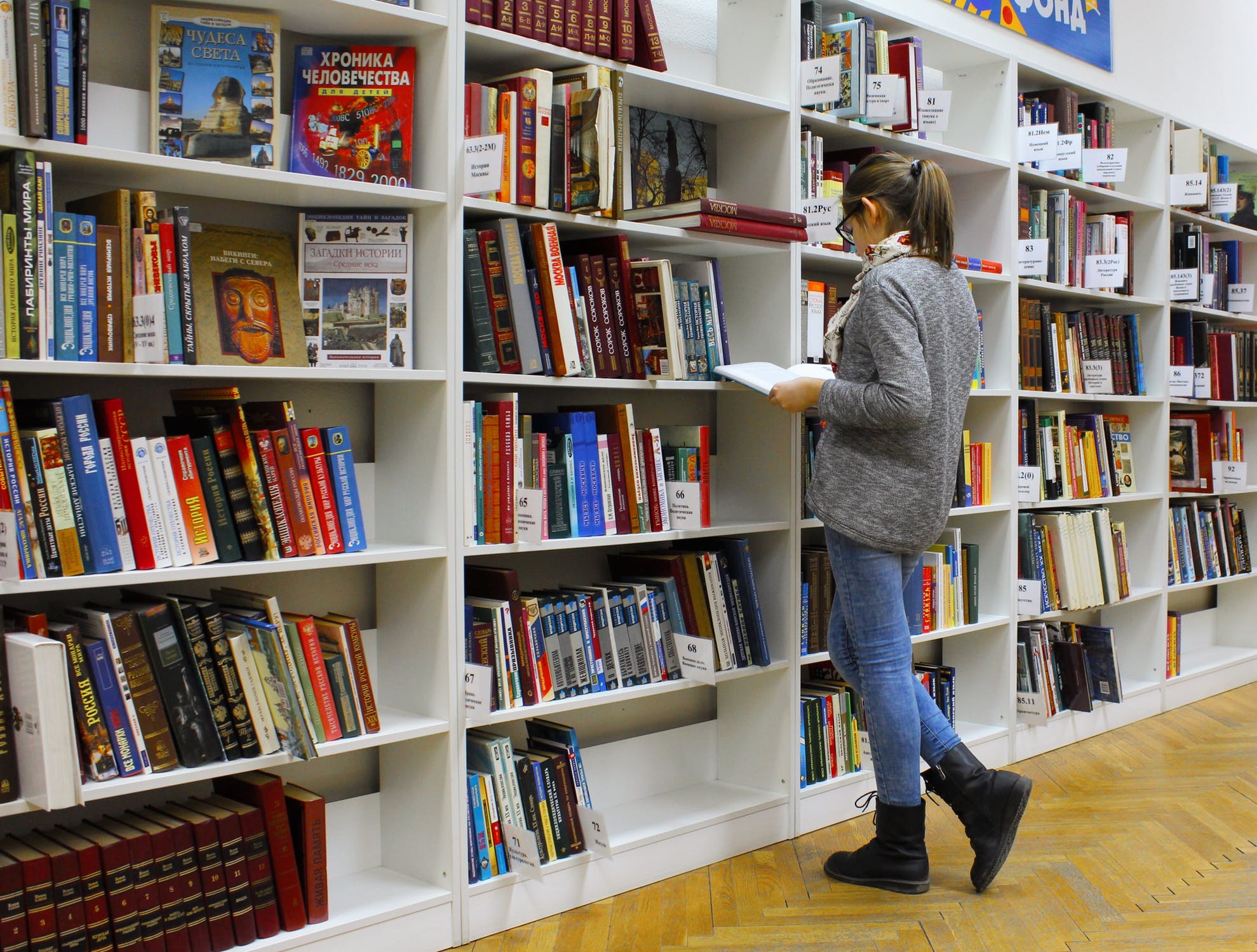 Student looking for books on a shelf.
