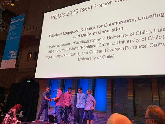 En la imagen, los académicos recibiendo el reconocimiento. La conferencia abarca temáticas de teoría y sistema de base de datos y reúne a los más destacados investigadores y empresas tecnológicas a nivel mundial. Es uno de los espacios más importantes e influyentes en el área de teoría de bases de datos y computación.