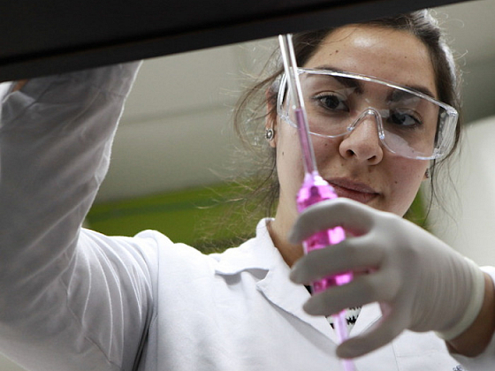 Una estudiante sosteniendo un instrumento en un laboratorio.