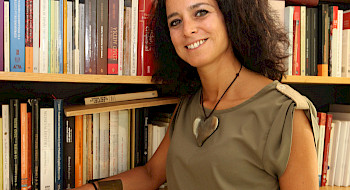 La académica Ximena Illanes posando junto a una biblioteca.