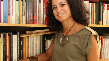 La académica Ximena Illanes posando junto a una biblioteca.