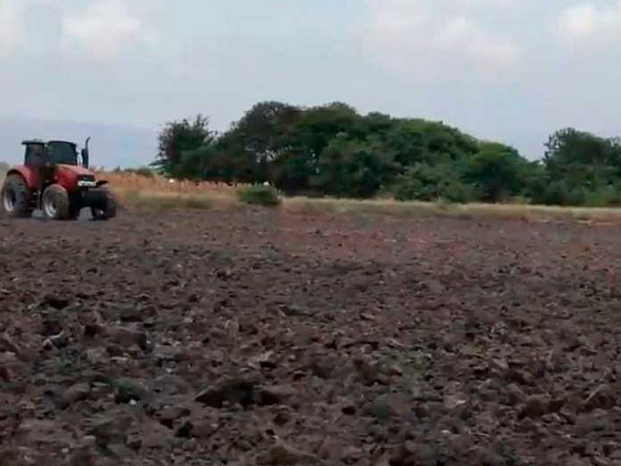 Un campo lleno de tierra, donde se ve un tractor.