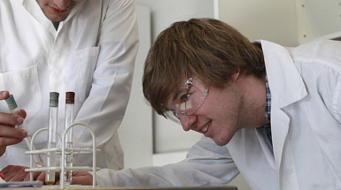 Dos estudiantes en un laboratorio mirando tubos de ensayo.
