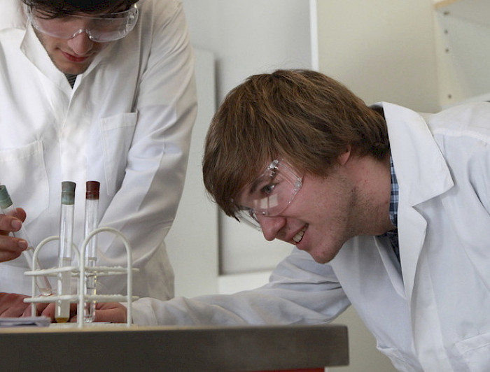 Dos estudiantes en un laboratorio mirando tubos de ensayo.