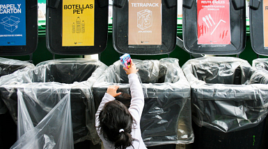 Niña pequeña dejando un envase Tetrapack en un punto de reciclaje.