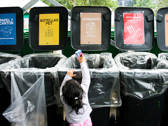 Niña pequeña dejando un envase Tetrapack en un punto de reciclaje.