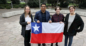 Grupo de extranjeros sosteniendo una bandera chilena.