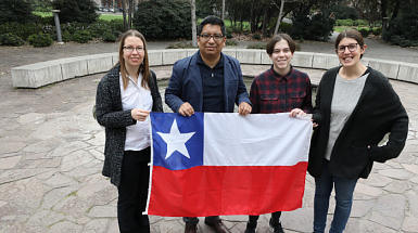 Grupo de extranjeros sosteniendo una bandera chilena.