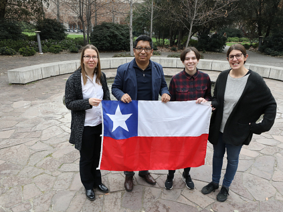 Grupo de extranjeros sosteniendo una bandera chilena.