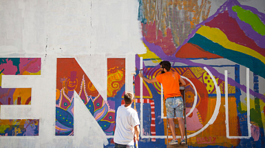 Dos hombres pintan el mural Simbiosis ubicado en la comuna de Recoleta