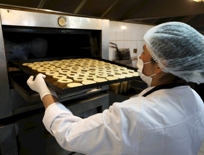 Una cocinera, dejando unos dulces en el horno.