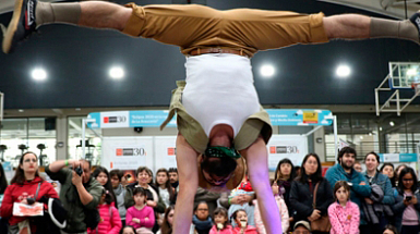 Una persona realizando una acrobacia en un escenario frente a un grupo de personas.