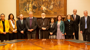 Miembros del comité de búsqueda del rector parados frente a una mesa redonda.