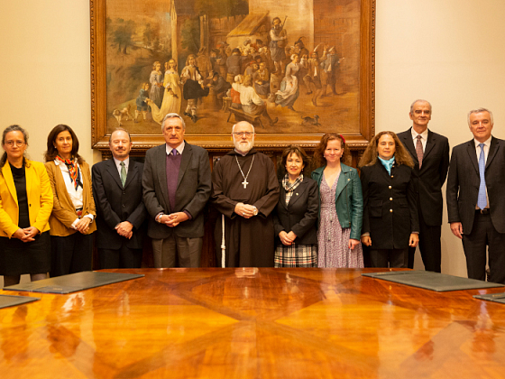 Miembros del comité de búsqueda del rector parados frente a una mesa redonda.