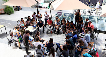Grupo de alumnos sentados conversando reflexivamente en el patio de Medicina UC.