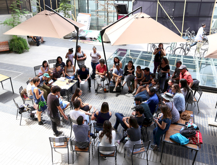 Grupo de alumnos sentados conversando reflexivamente en el patio de Medicina UC.