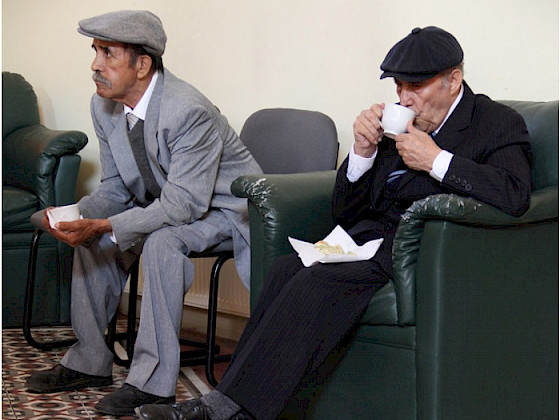 Dos adultos mayores sentados en una sala.