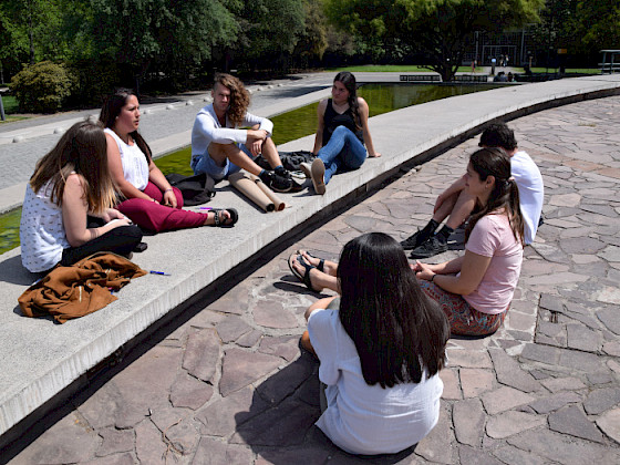 Grupo de mujeres sentadas en el suelo conversando.